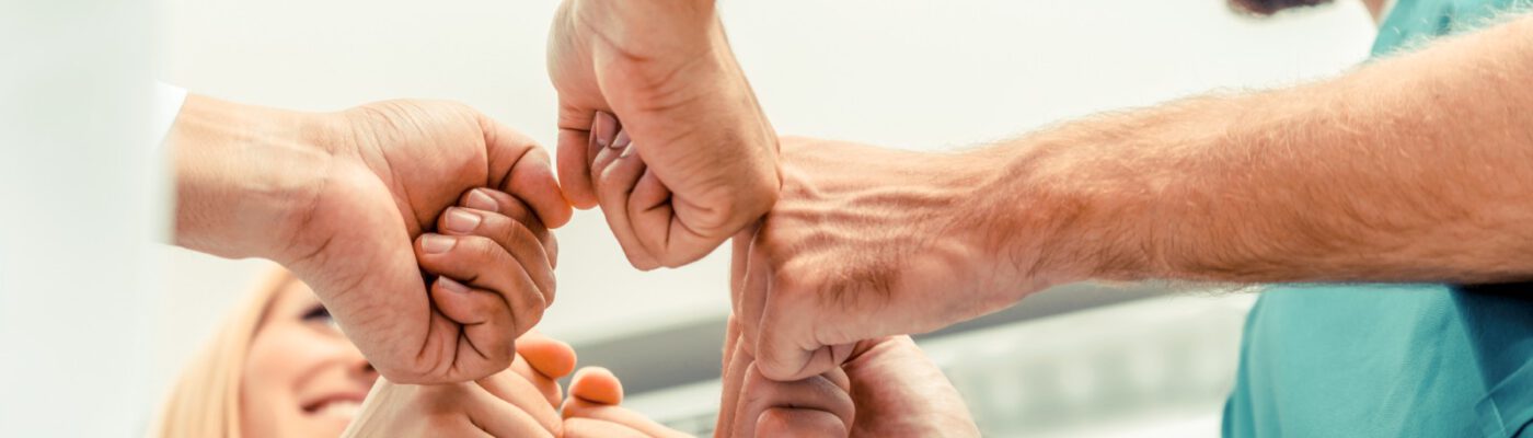 Teamarbeit im medizinischen Dienst - Arzt, Chirurg und Krankenschwester reichen sich die Hände.