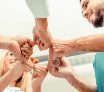Menschen in Pflegekleidung bilden einen Kreis aus ihren Händen