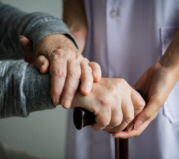 Nahaufnahme von den Händen einer Pflegerin und eines alten Menschen